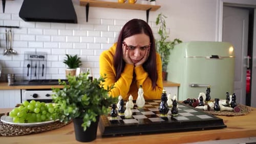 Jeune femme attentionnée jouant aux échecs à la recherche de mouvements possibles