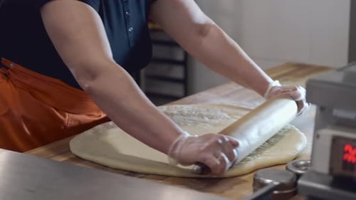 Woman Rolling Dough in Commercial Kitchen
