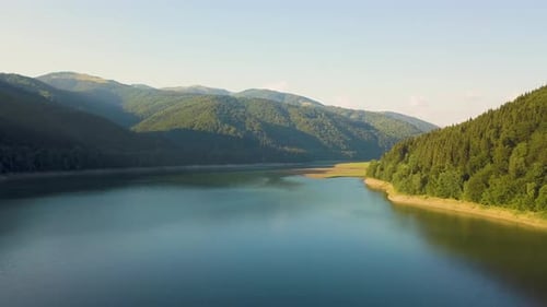Aerial View of Big Lake with Clear Blue Water Between High Mountain Hills Covered with Dense