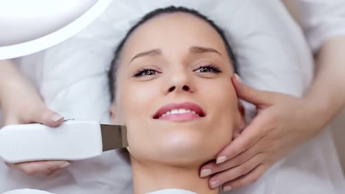 Top View Handsome Young Woman Enjoying Ultrasonic Peeling Cleansing Procedure at Beauty Salon