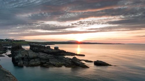 Time lapse with colorful sunset sky at rocky coastline