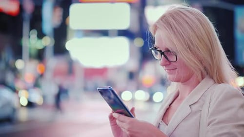 Mulher de óculos usa um smartphone na famosa Times Square em Nova York