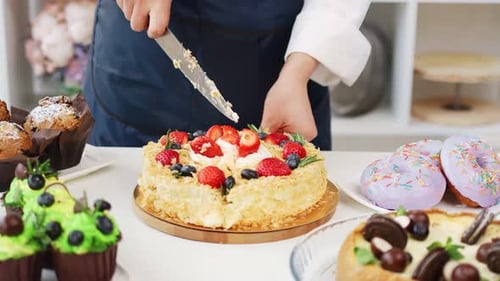 Cutting Fruit Layer Cake Among Other Sweets