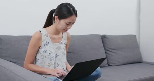 Woman Working on Laptop While Relaxing on Couch