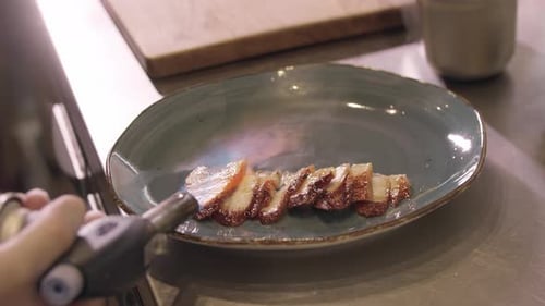 Restaurant Cooking Chef Burns Slices of Fish with a Burner
