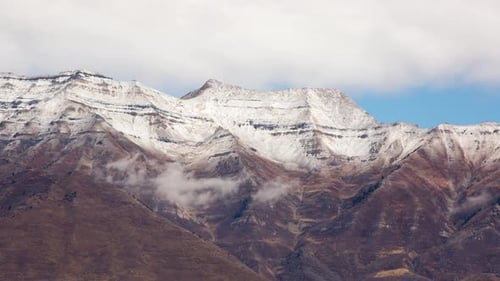 Time lapse of snowy mountain top as clouds move by