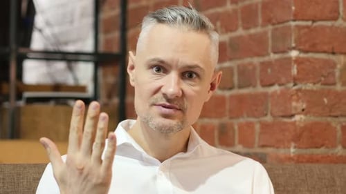 Man Speaking and Gesturing Toward the Camera