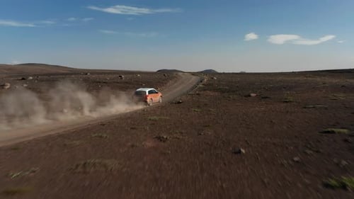 Car Moving on Dirt Road Leading Through Barren Volcanic Plain