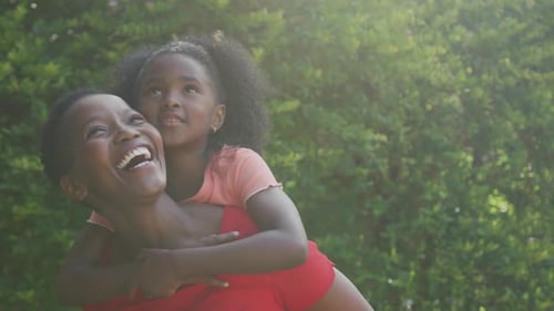 Happy Woman Gives Child Piggyback Ride Outdoors
