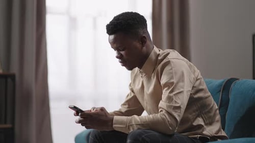 Young Adult on Phone Sitting on Teal Sofa