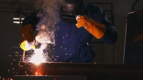 Welder Working with Protective Gear in a Workshop