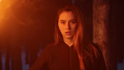 Young Woman with Braces Waving with Torch Standing in Winter Forest