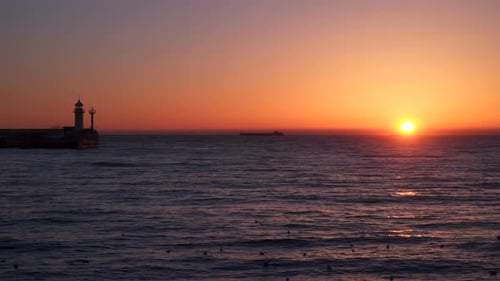 Sunrise Over the Sea We See a Cargo Ship On the Horizon Pier With a Beacon