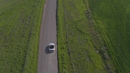 Car Driving On The Dirt Road Among Windmills