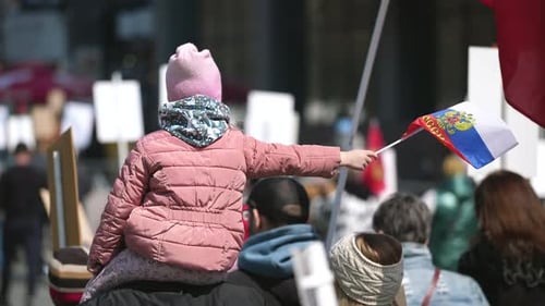 Child Waves Flag from Shoulders in Crowd