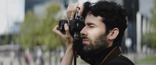 Man Holding a Vintage Camera in a City