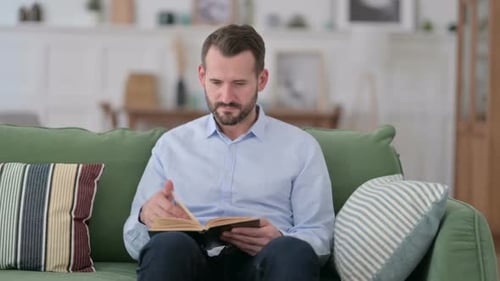 Man Reading Book on Sofa Indoors