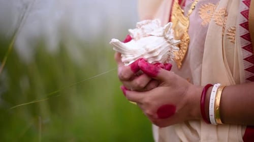 Les mains d'une Indienne récemment mariée vêtue d'un sari tenant un shankha ou une conque dans un champ