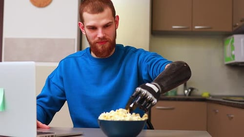 Man With Prosthetic Arm Eats Popcorn and Laughs