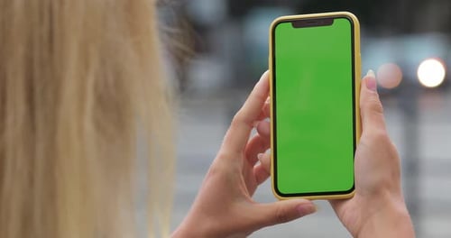 Overshoulder View of Unknown Woman Holding Smartphone Green Screen with Both Hands. Close Up View of