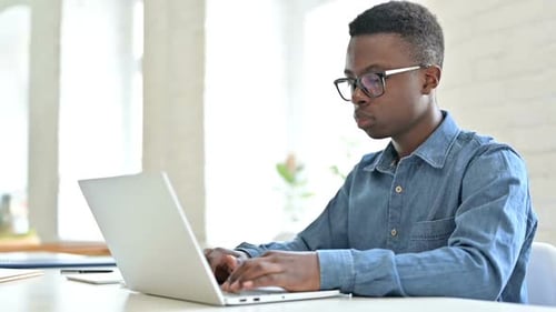 Young African Man with Laptop Shaking Head in Denial No Sign
