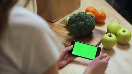 Closeup of Woman's Hand Browsing Smartphone with Chroma Key on Kitchen at Home, Breakfast Browse