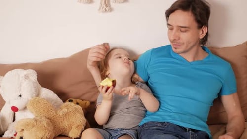 Father and Daughter Sharing an Apple Indoors
