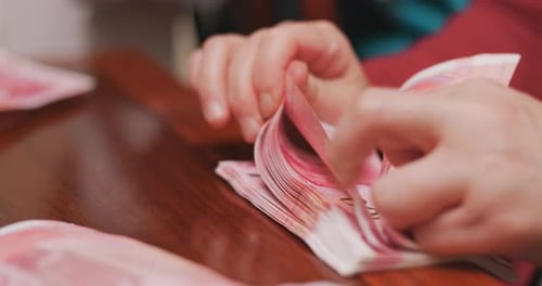 Hands Counting Pink Money on Table