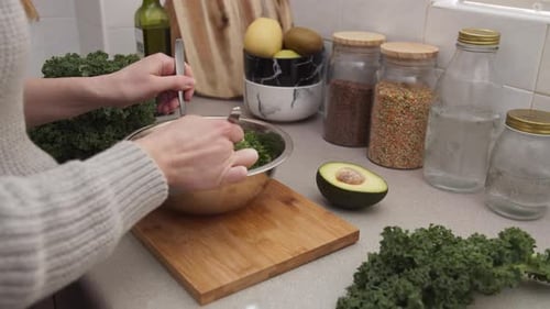Woman Mixing Fresh Green Salad in Kitchen