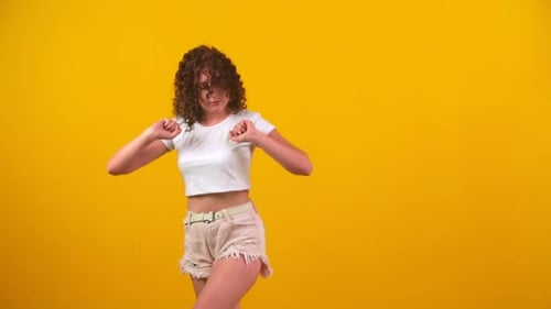 Excited Woman Dancing in Front of Yellow Background