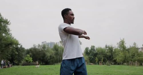 Sporty African Man with Warm Up By Stretching Arms Before Running in City Park