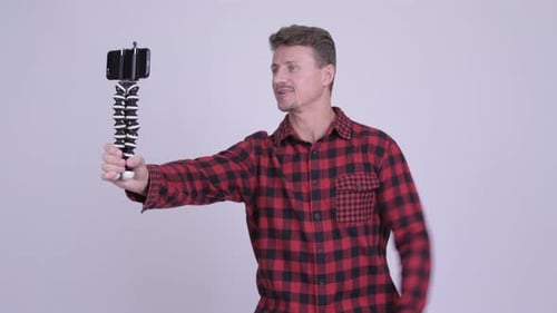 Man Filming Himself with Phone on Tripod