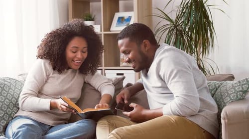 Couple Relaxing at Home Reading and Using Smartphone
