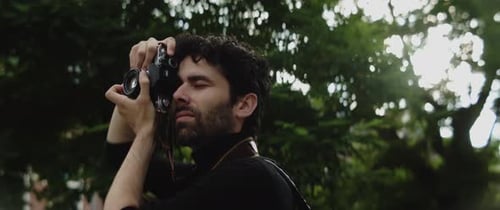 Man Takes Photo with Analog Camera in Park