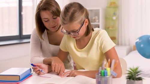 Woman Helping Girl with Schoolwork at Table