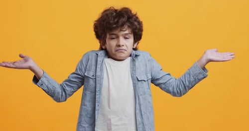 Niño despistado y perplejo que se encoge de hombros y sacude la cabeza en contra, expresando incertidumbre
