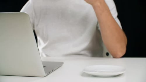 Mann arbeitet am Notizbuch und trinkt Kaffee am Arbeitstisch. Onlinemanager im weißen T-Shirt Holding