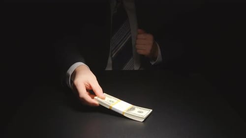 Suit-clad Person Puts Stack of Cash on Table