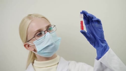 Young Adult Inspecting Vial in Laboratory