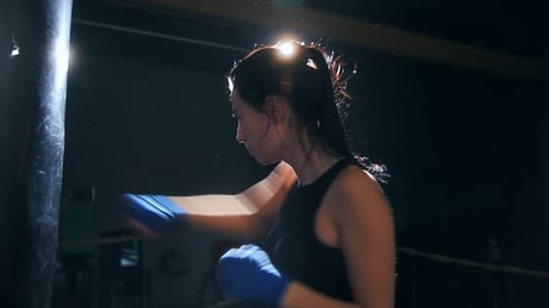 Strong Woman Boxing with Punching Bag in Gym