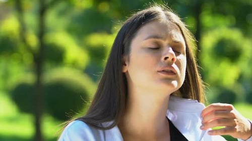 Jeune femme souffrant de chaleur assise dans le parc, agitant la main et essayant de se refroidir