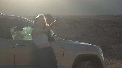 Woman Taking Selfie by Car in Desert at Sunrise