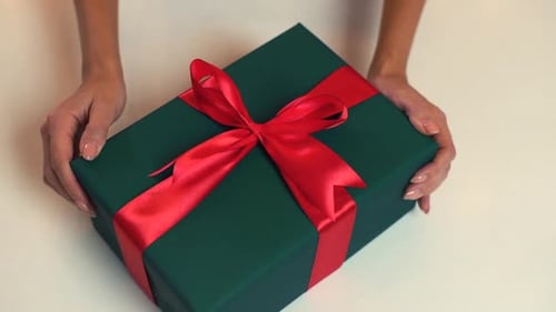 Closeup Top View Hands of Unrecognizable Young Woman Moving Gift Box and Using Ribbon to Tie Bow for