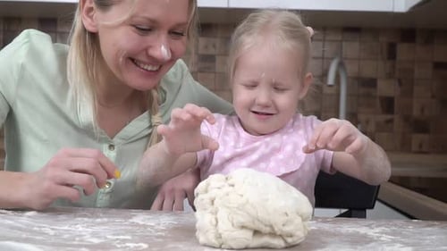 Mother and Daughter Kneading Dough Together in Kitchen