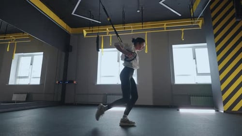 Athletic Woman Doing TRX Lunges in Gym