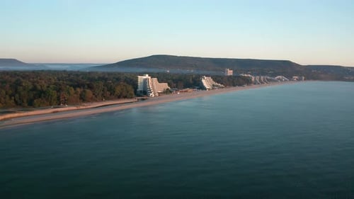 Drone flight over empty sandy beach and coastal hotels