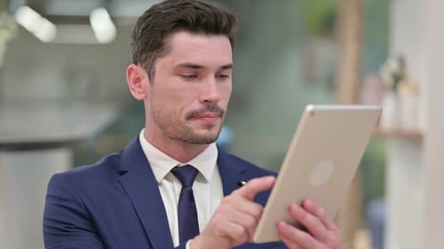 Man Works on Tablet Indoors Close Up