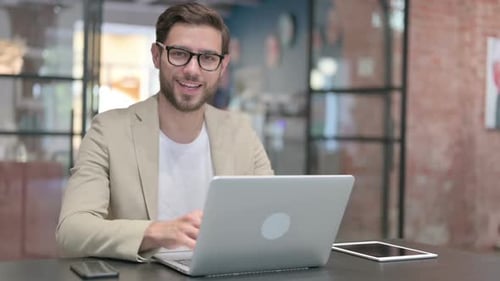 Man Using Laptop Gives Thumbs Up Indoors