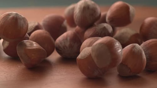 Hazelnuts Falling onto Wooden Surface, Close Up
