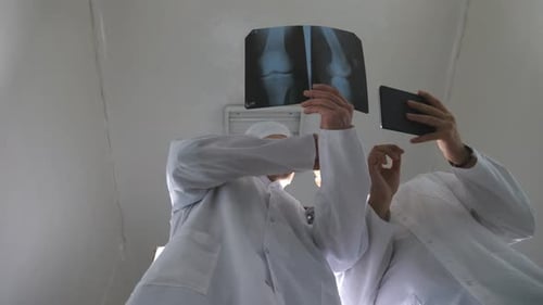 Male Medics Using Tablet Pc While Consult with Each Other About x Ray Image of Patient